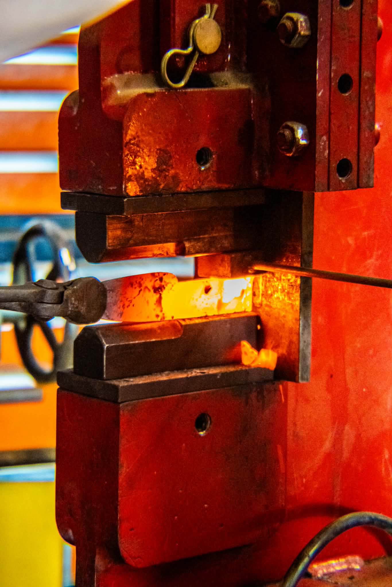 A hydraulic press squeezing a yellow-hot steel billet