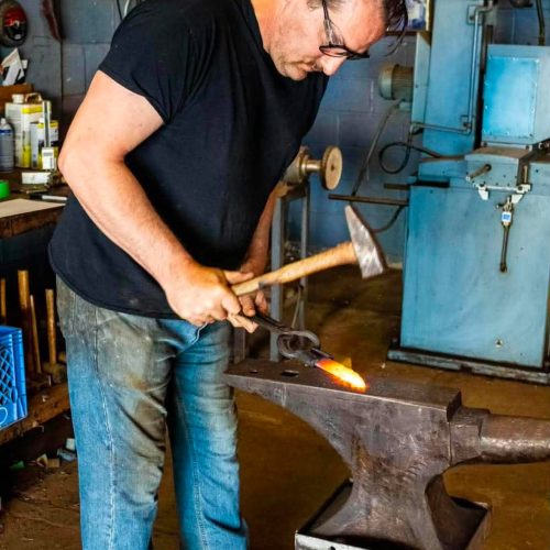 Seth Boehnke drawing out hot steel on the anvil with a hand hammer
