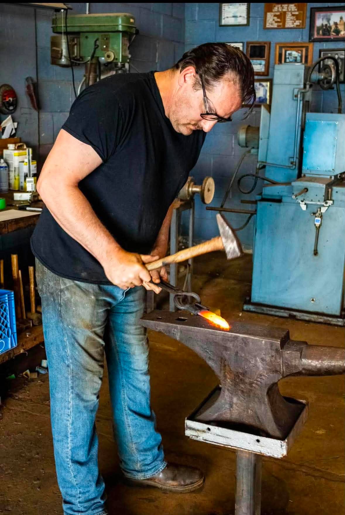 Seth Boehnke drawing out hot steel on the anvil with a hand hammer