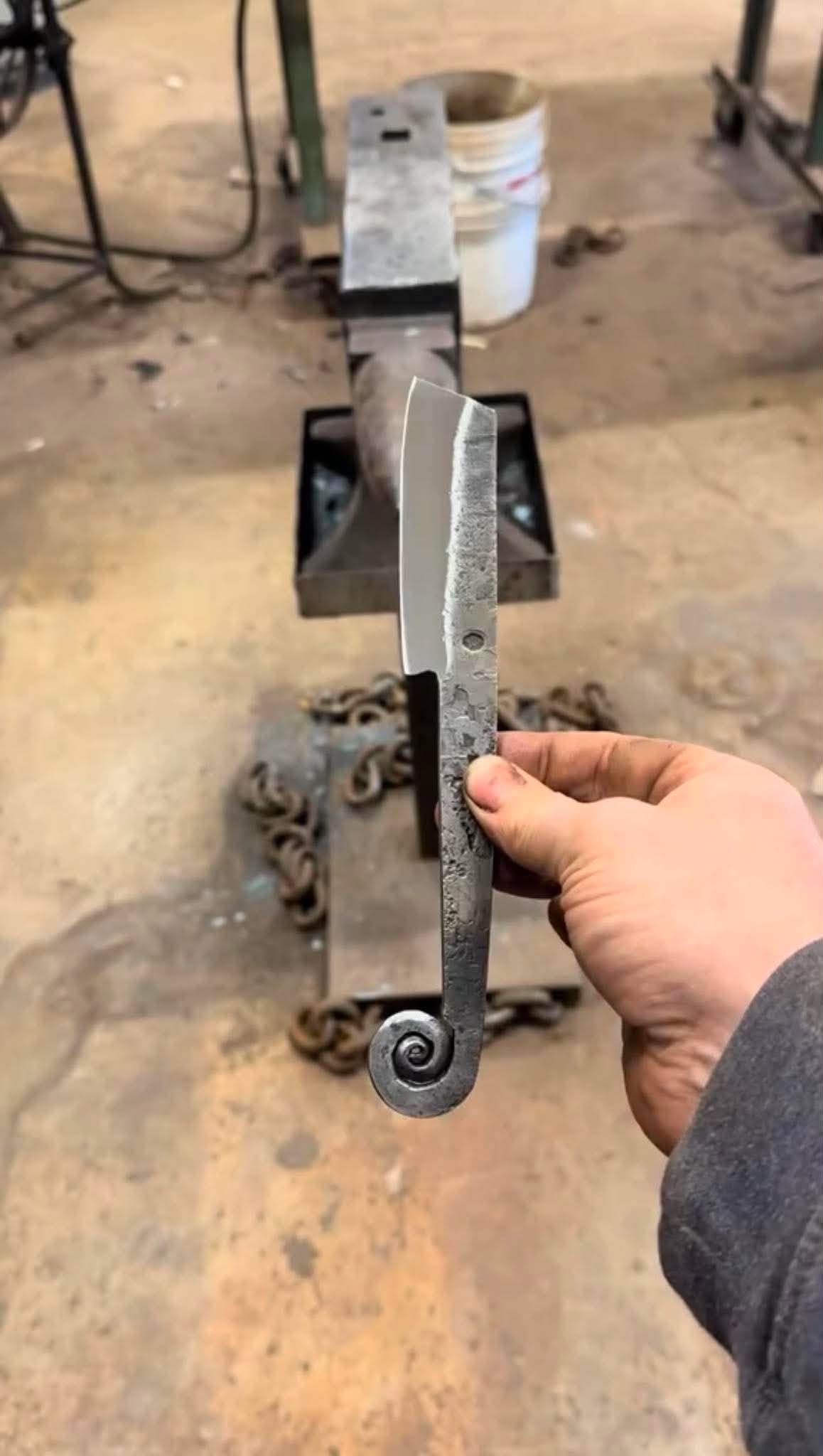 A small forged cleaver whose tang is drawn out and scrolled into a hook at the end